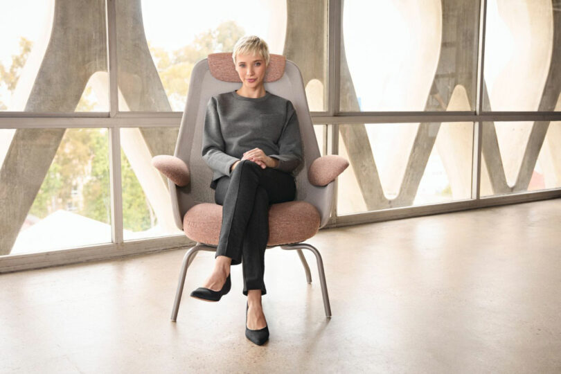 A pink Teknion armchair positioned against a geometric concrete window frame with natural light.