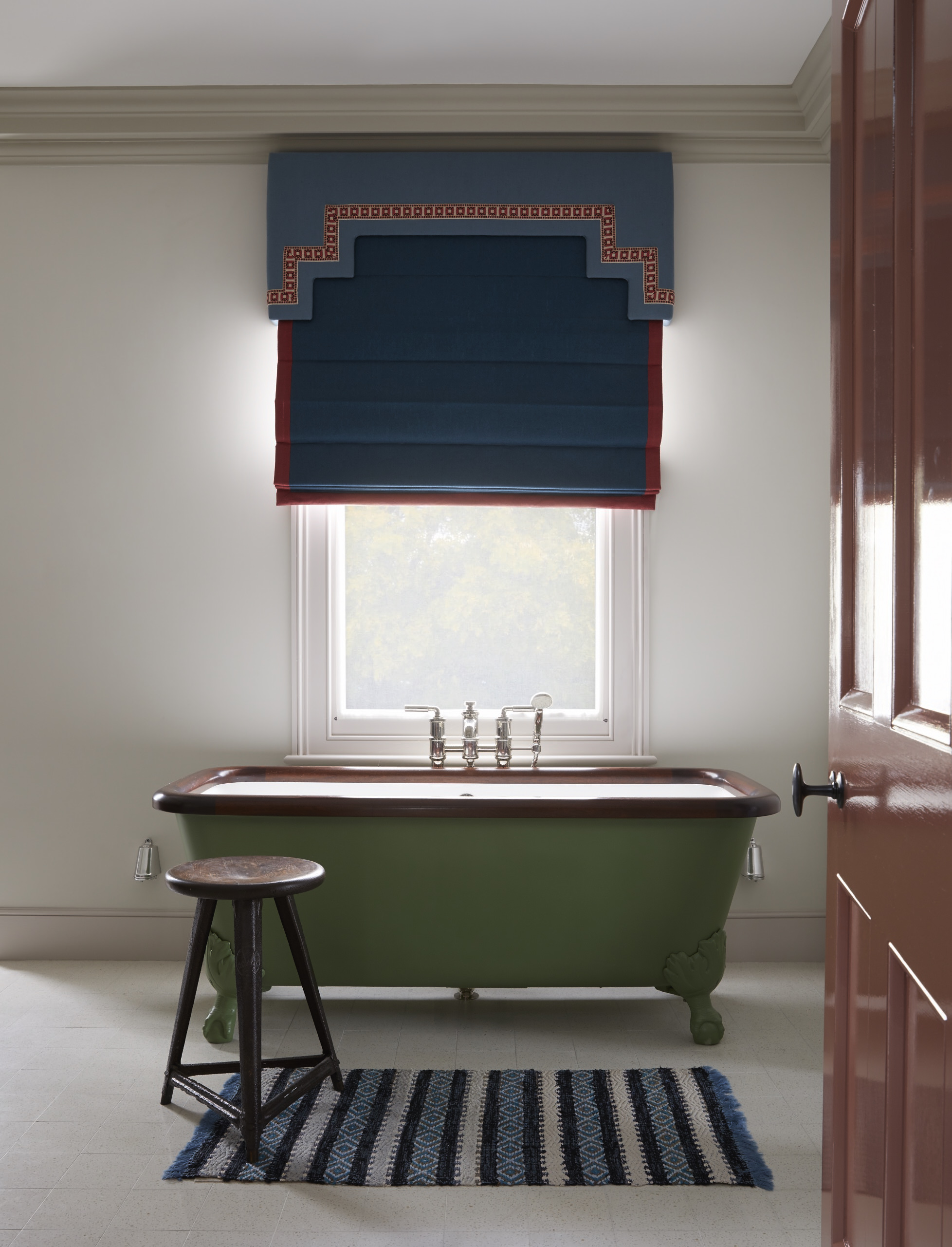 A bathroom with pastel walls, fawn trim, and a clawfoot tub painted in a rich, natural green.