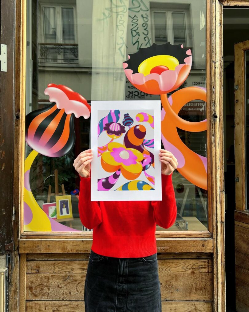 An abstract art print held up against a matching mural on a storefront window.