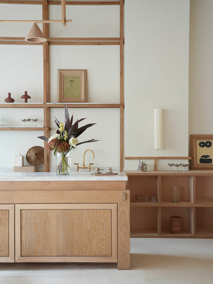 Minimalist kitchen featuring eucalyptus wood cabinets, white countertops, and a gold faucet.