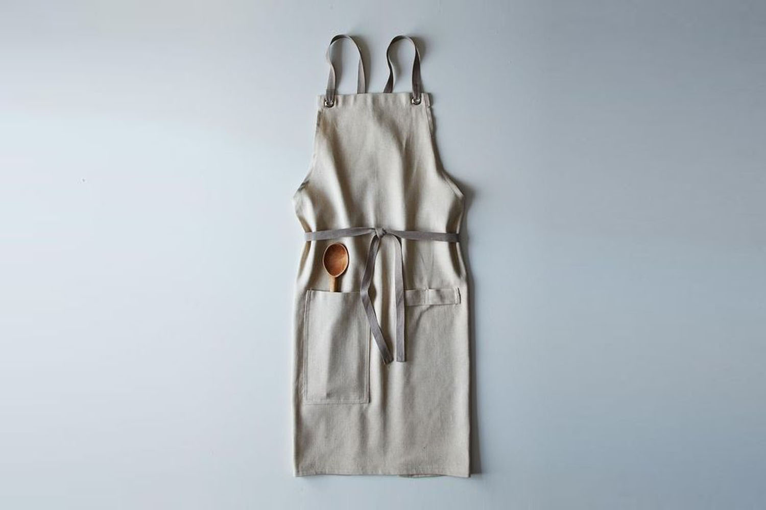 A linen kitchen apron featuring a cross-back strap design that eliminates neck strain.