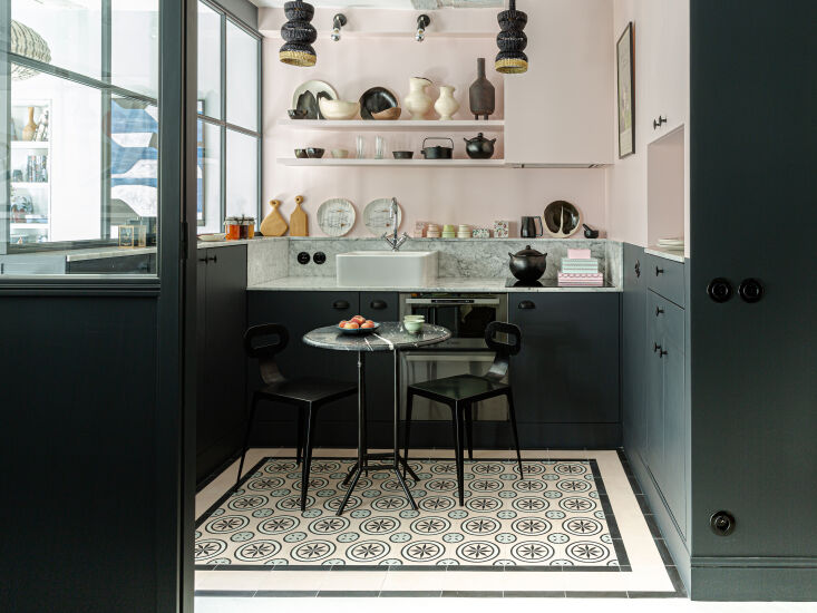 A white half-glazed glass wall dividing a kitchen from a living area with soft color tones.