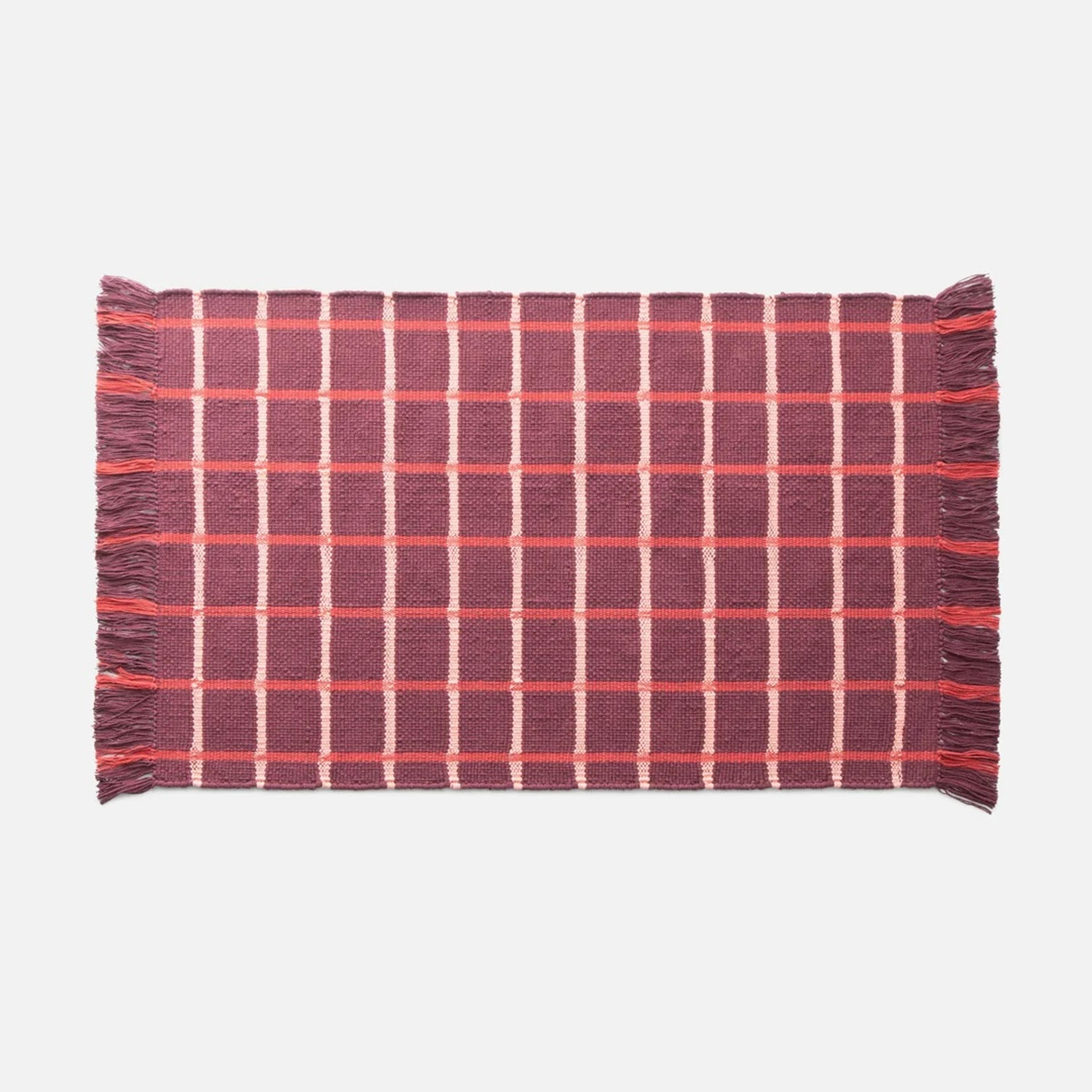 A modern grid-patterned cotton rug in a well-lit living space.