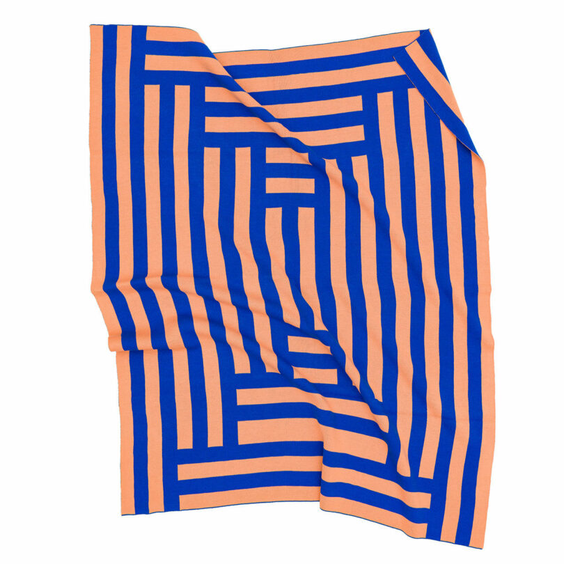 A blue and peach geometric jacquard knit textile with a maze-like pattern.