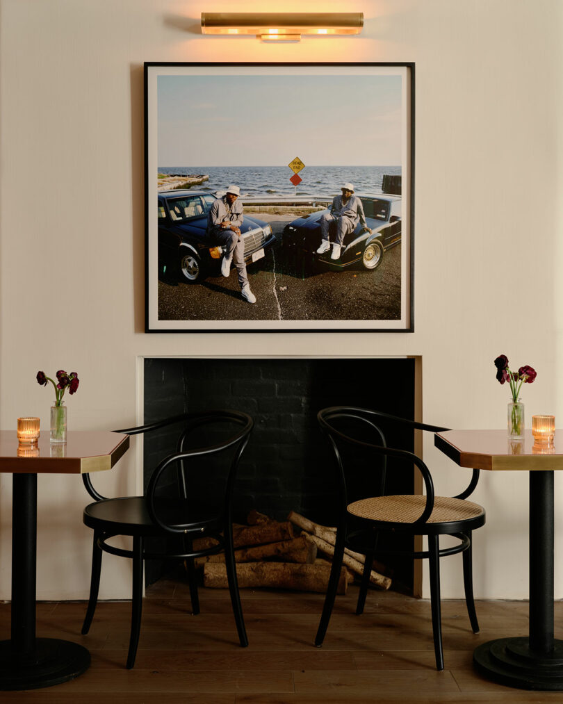 A framed photograph of two people by the sea hanging above a black fireplace in a dimly lit lounge.