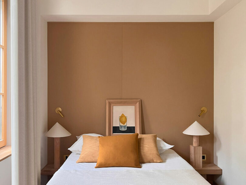 A minimalist bedroom with symmetrical eucalyptus nightstands and a brown accent wall.