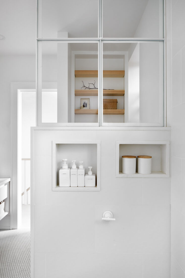 A modern shower with white fixtures and a black-framed glass panel.
