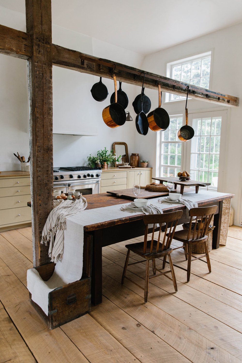 Rustic kitchen interior with copper pots hanging from a rack and exposed timber framing.