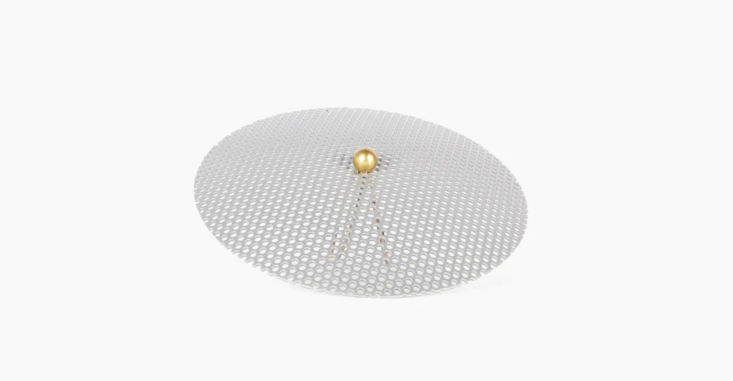 Modern silver mesh lampshade with a gold accent ball against a clean background.