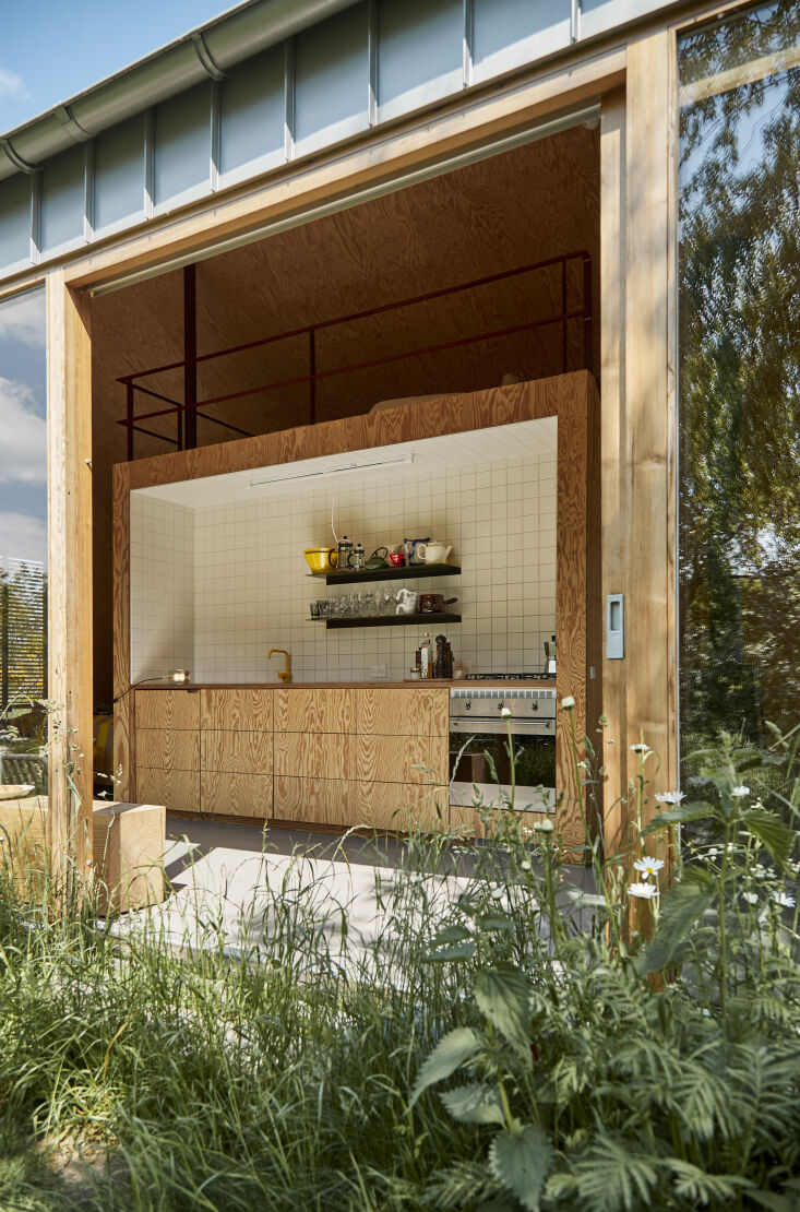 Interior view showing a central wooden core housing the kitchen with a yellow faucet and a loft above.