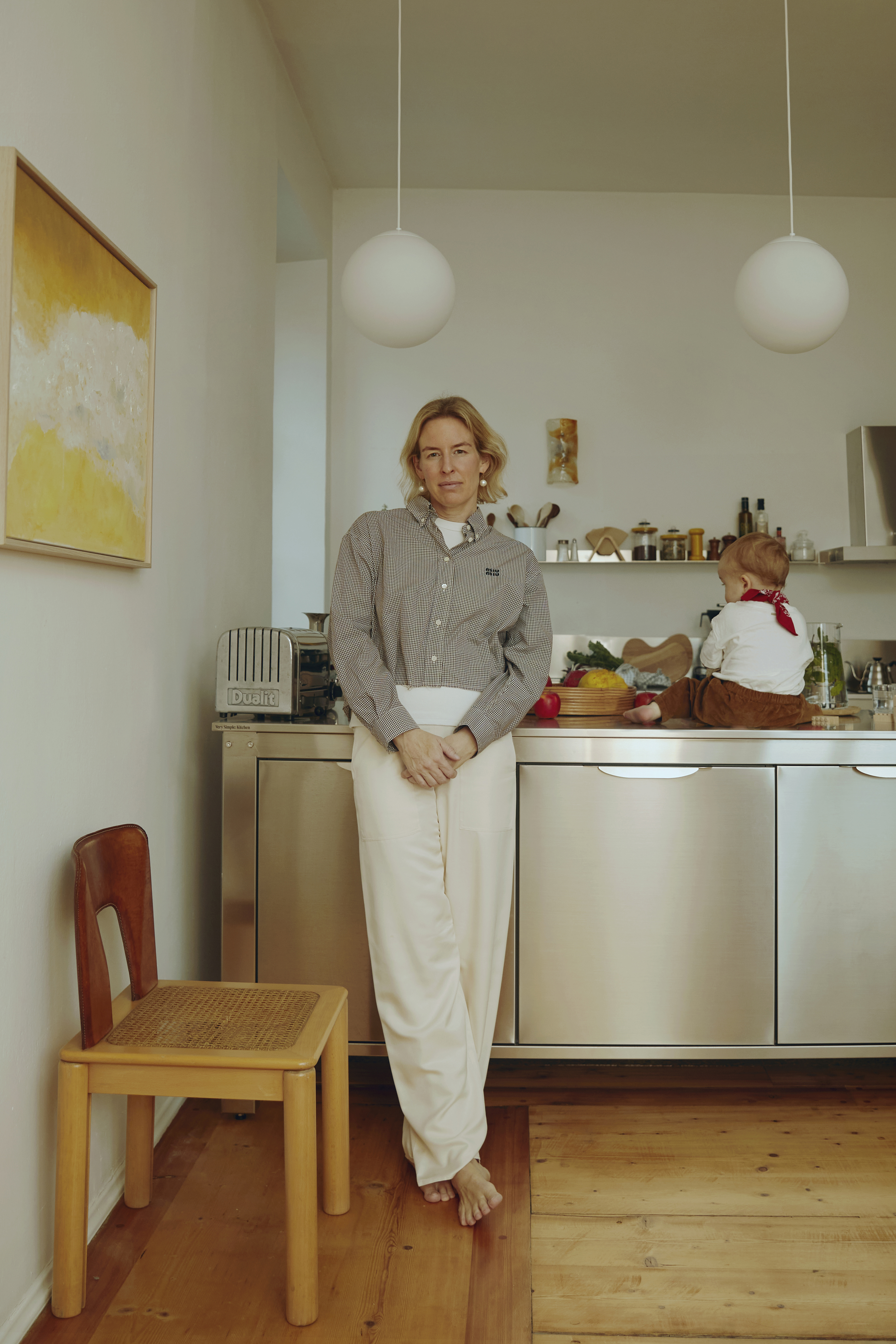 Century-old pine flooring in a light-filled apartment featuring a vintage Tobia Scarpa chair and globe pendants.
