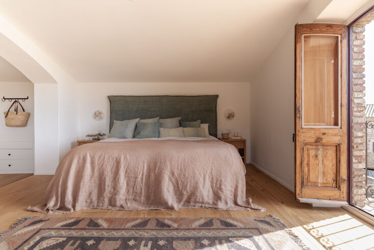 A bedroom featuring a custom hand-painted cloth headboard by Espanyolet.