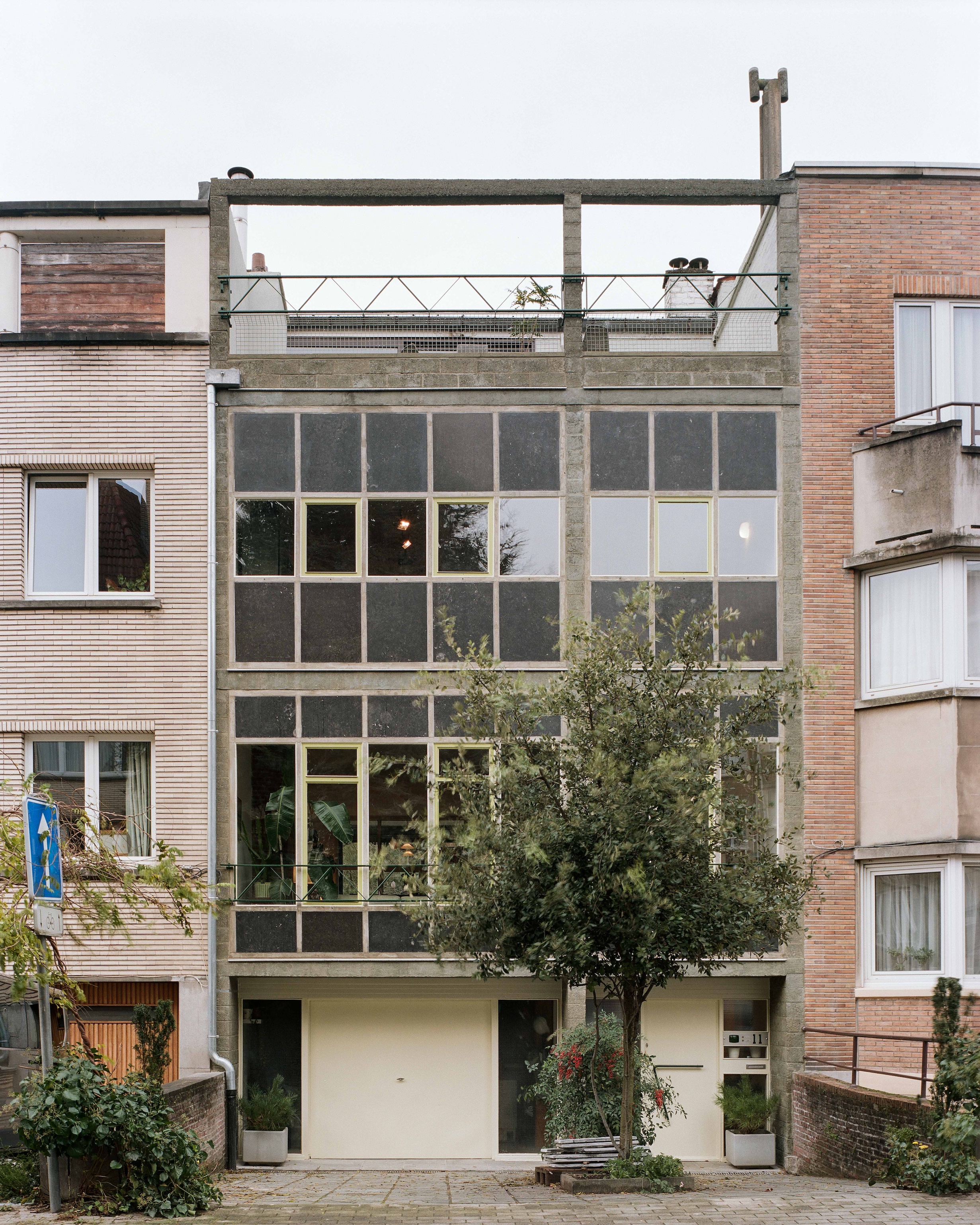 The exterior facade of the Moreau House showing exposed concrete slabs and the third-floor addition.