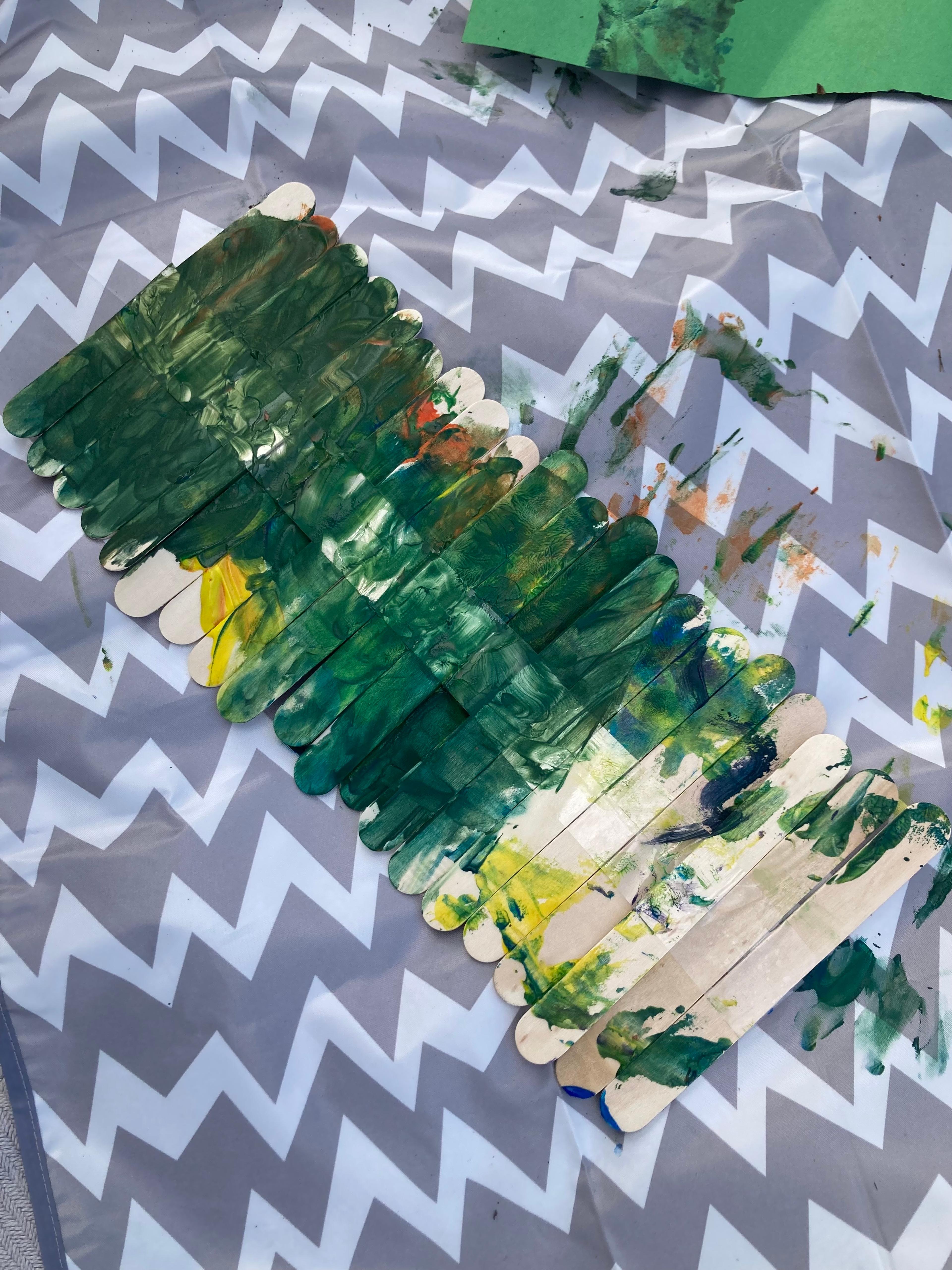 Colorful popsicle sticks used as plant markers in a garden row, with names written in child's handwriting.