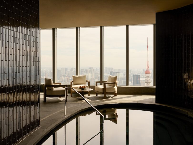 A serene indoor pool area with lounge chairs looking out over the Tokyo skyline and Tokyo Tower.