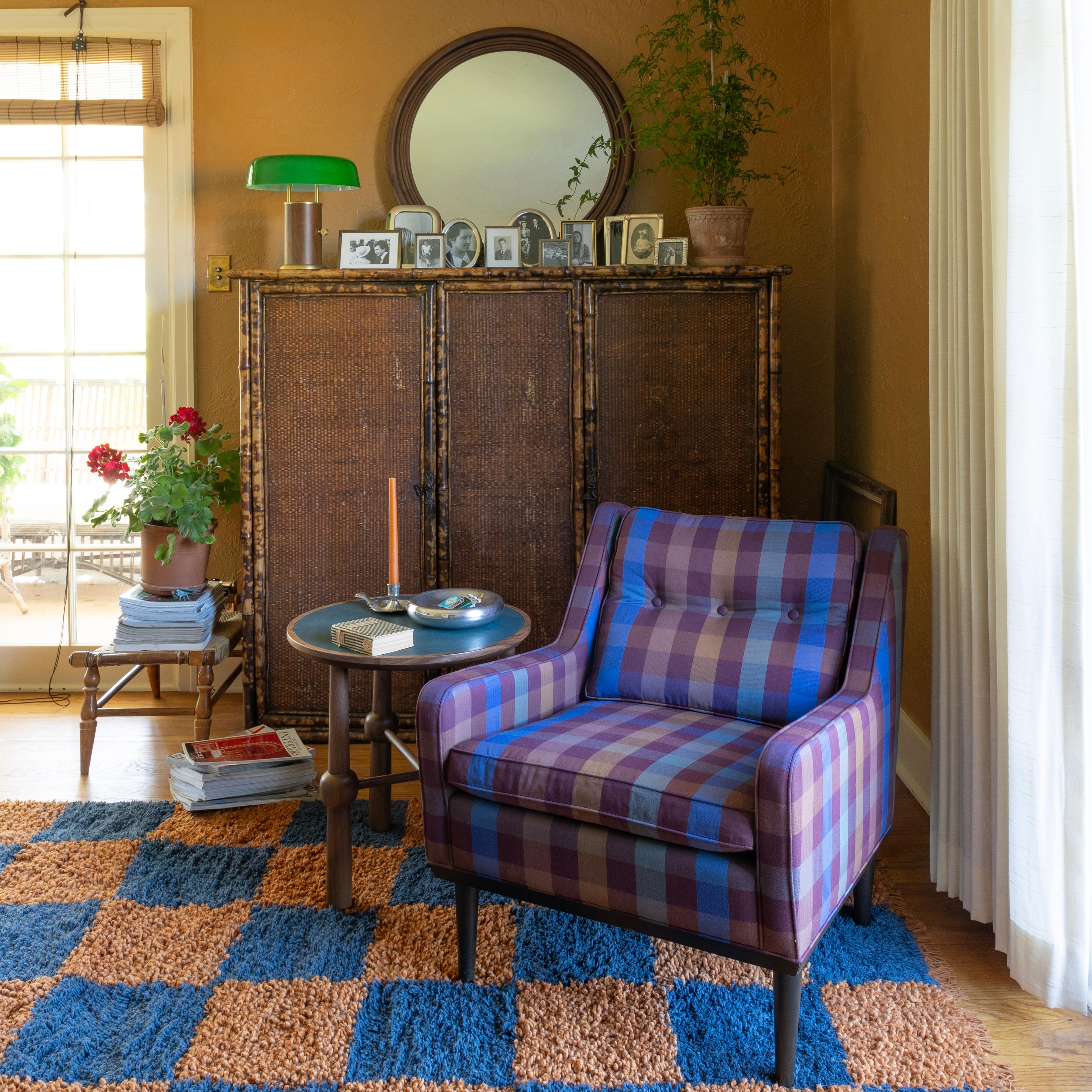 A patterned armchair next to a shelf and a mirror, creating a cozy and personalized reading nook.