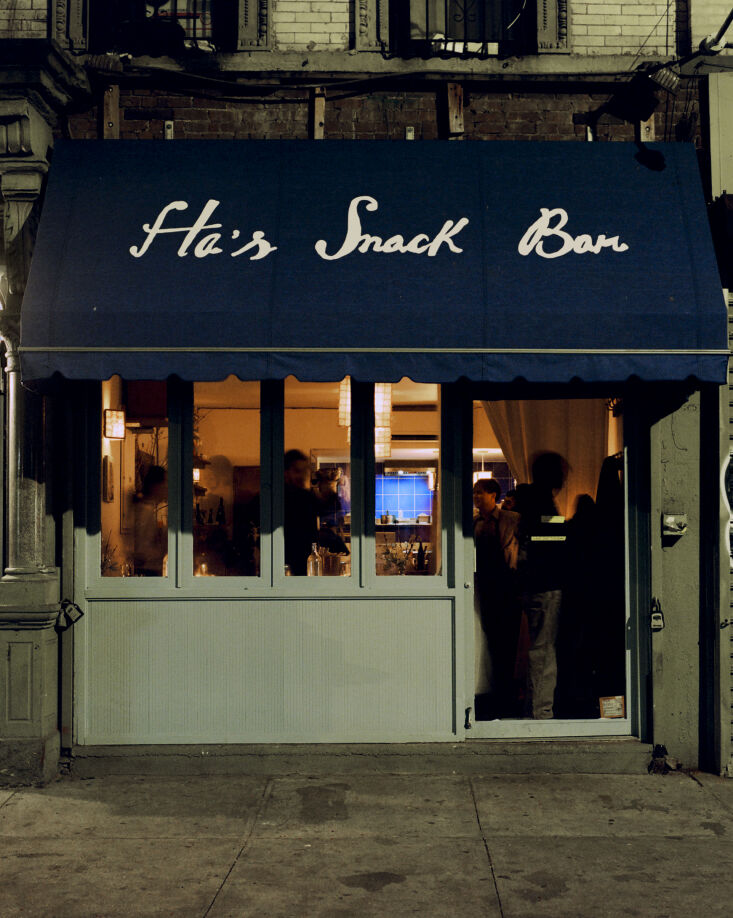 A bustling evening scene at Ha’s Snack Bar with patrons dining and drinking wine.