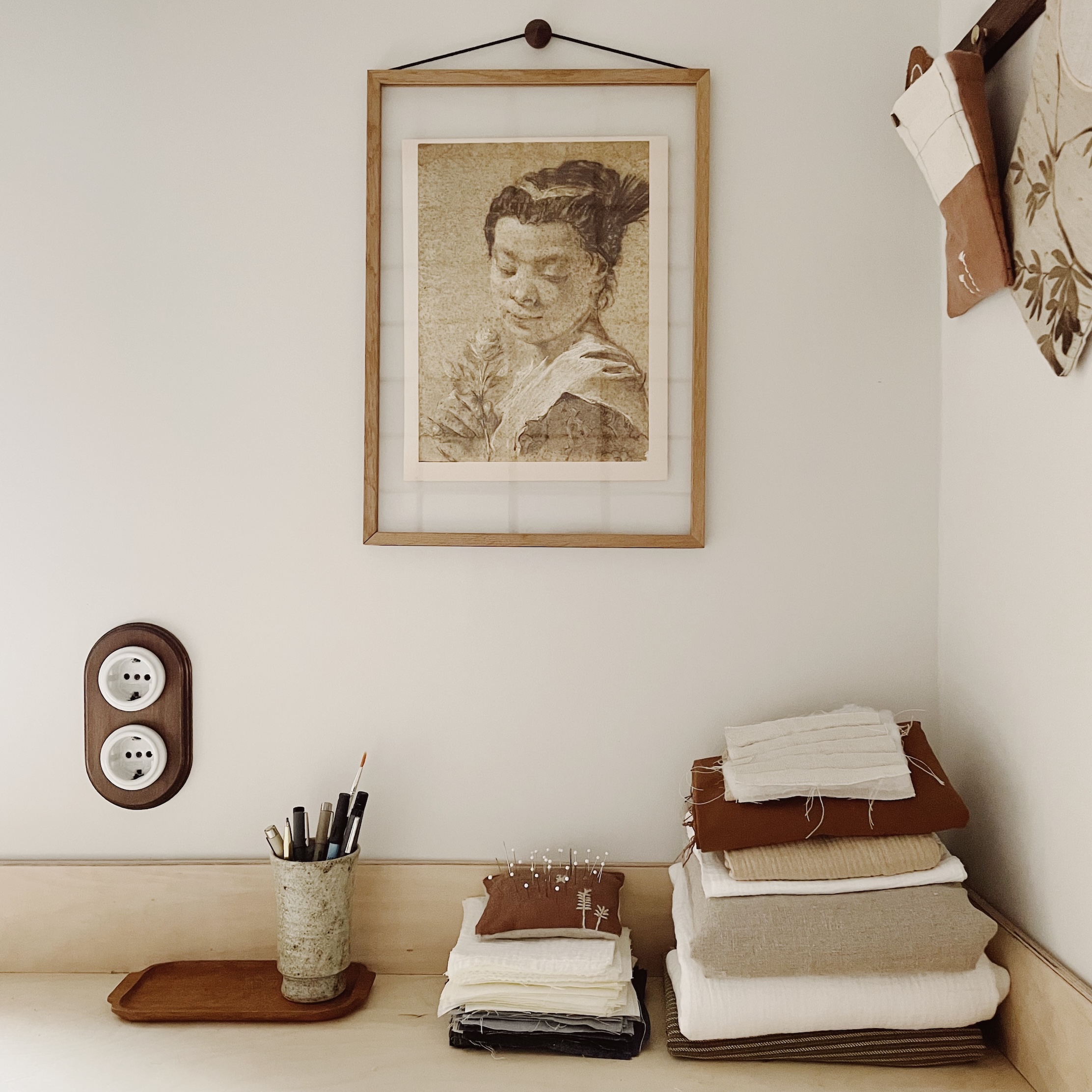A vintage-style porcelain double electrical outlet with an antique wood frame near quilting supplies.