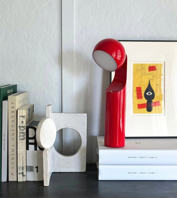 The red Mono Portable Lamp with a rotating head on a desk.