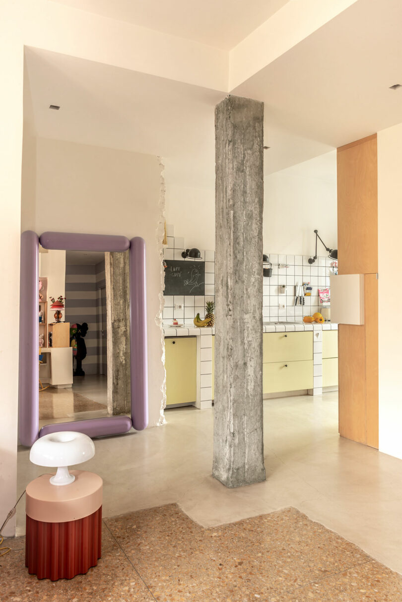 Close-up of a kitchen with yellow cabinets and a central concrete pillar.