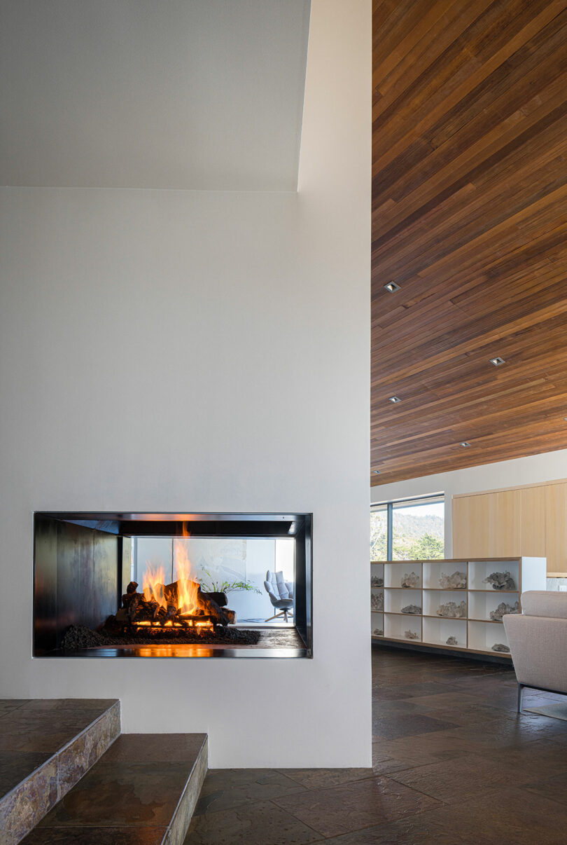 Interior shot featuring a stone floor, wooden ceiling, and a built-in glass fireplace.