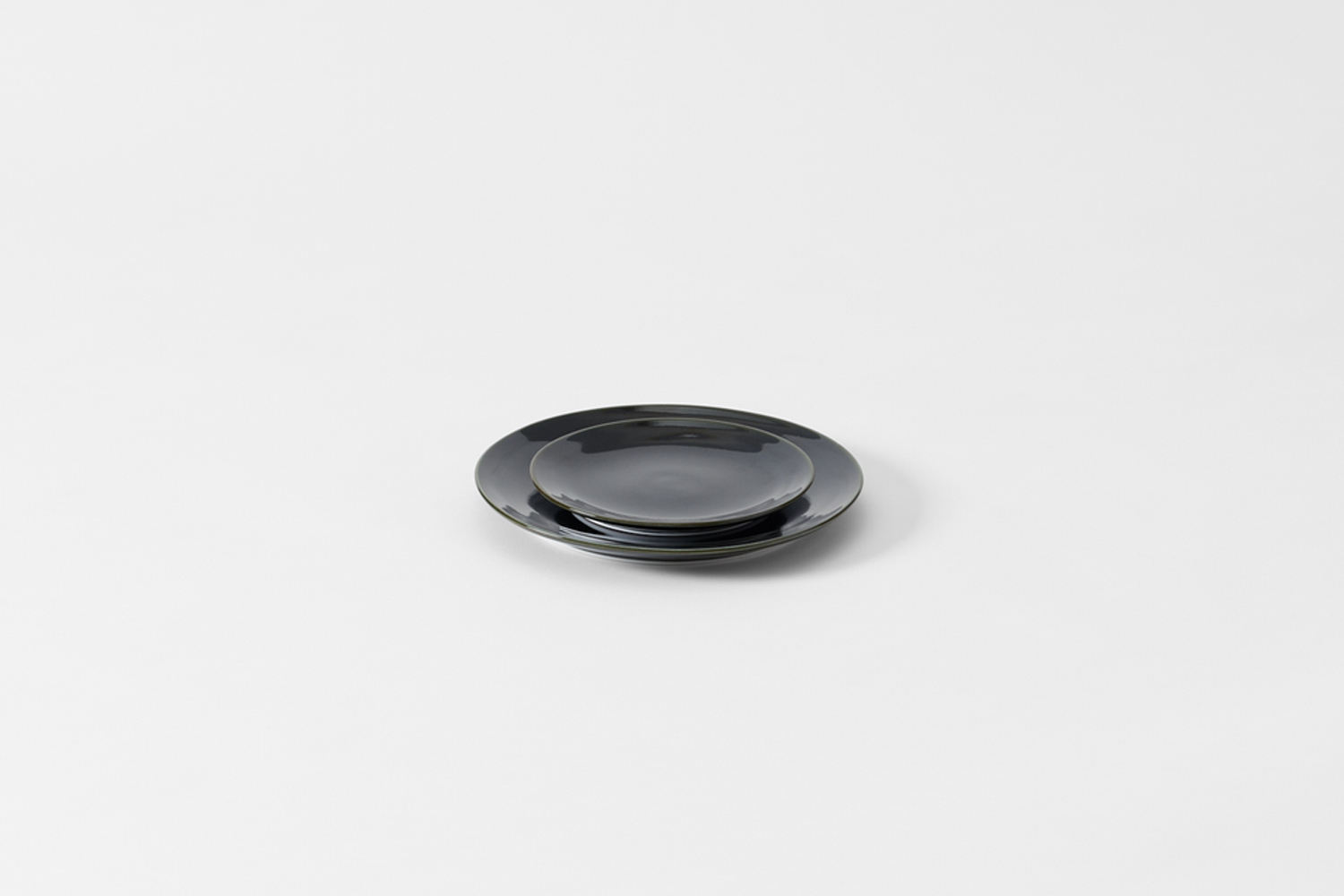 Close-up of glossy black ceramic dinner plates showcasing the smooth reflective surface and clean edges.