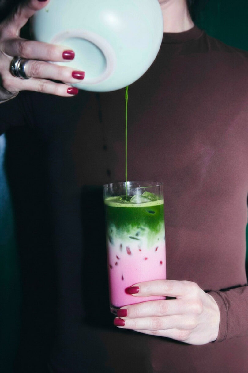 Matcha being poured into a layered iced drink, showcasing vibrant green hues.
