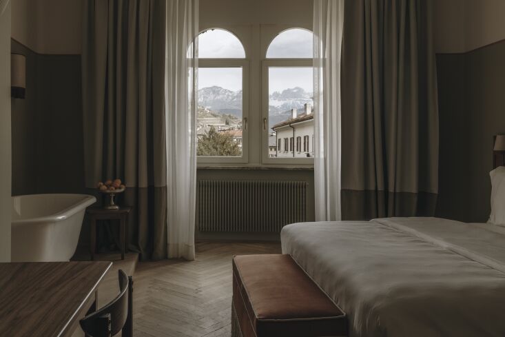 Luxury bedroom with arched windows and mountain views at Parkhotel Mondschein.