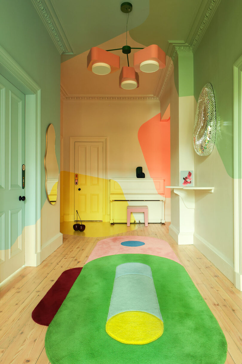 Hallway with pastel doors and a geometric-patterned rug showing a cohesive colorful design.