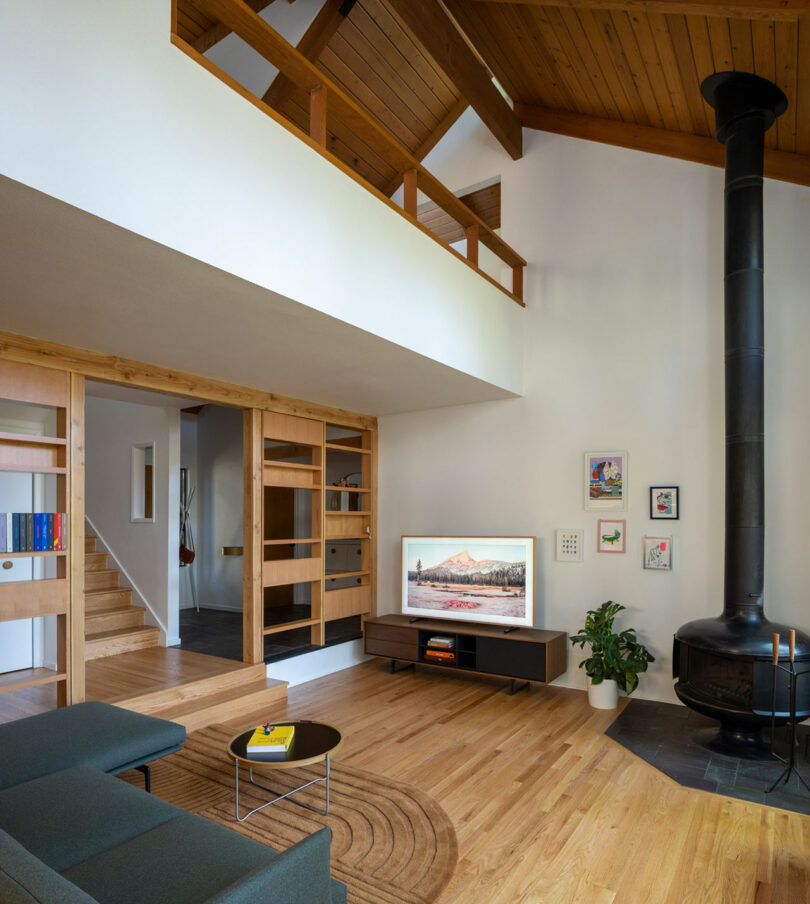 Modern living room with high vaulted wood-beam ceilings and a black minimalist fireplace.
