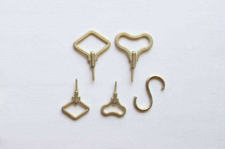 Geometric brass hooks displayed on a clean white surface representing Japanese metal craftsmanship.