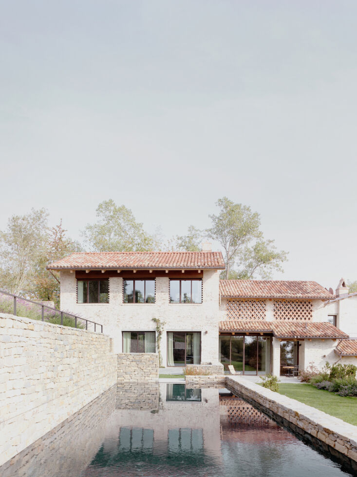 The swimming pool and stone walls integrated into the sloping landscape of the Cascina estate