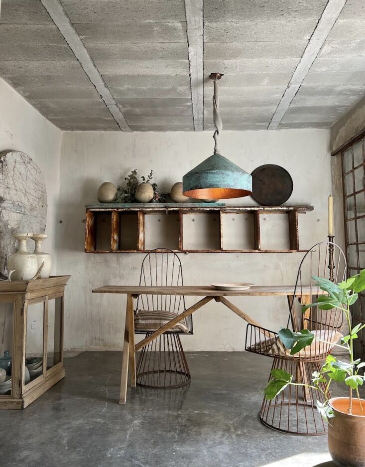 Minimalist dining room with sand-colored walls and a hanging copper light fixture.