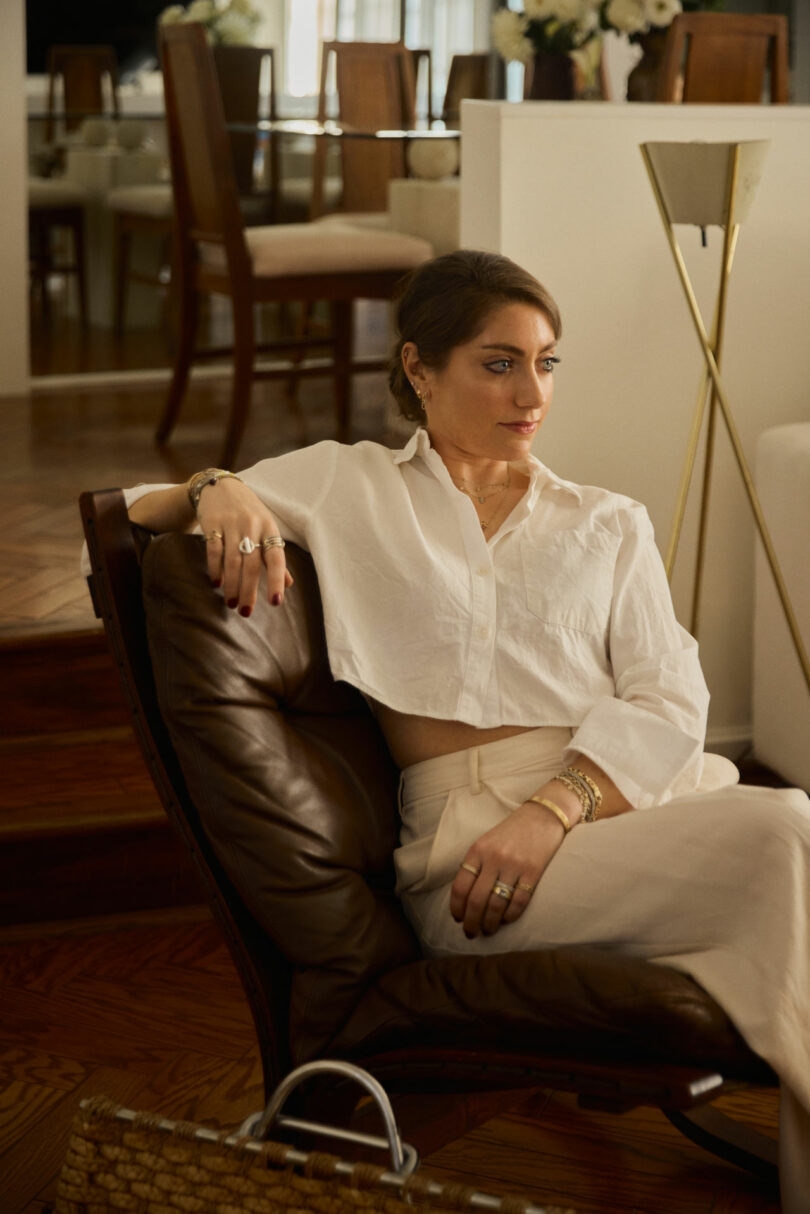 Interior designer Coco Greenblum sitting in a leather chair within a modern living space.