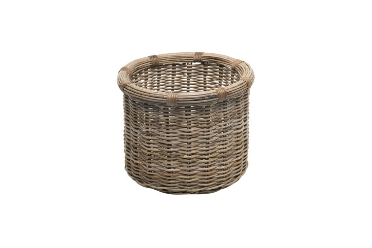 A simple woven rattan basket used for storage in a minimalist room.