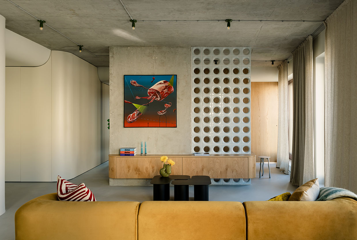 A structural concrete column wrapped in glass blocks next to a minimalist art piece.