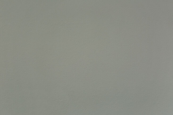 A living room wall painted in a soft Smoked Green-Blue tone.