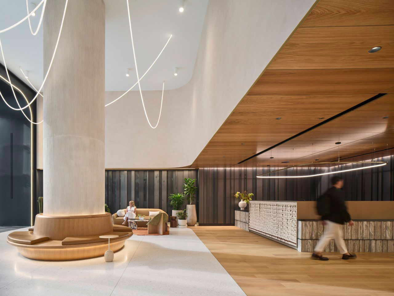 Expansive lobby with a curved wood-slat ceiling, sculptural seating, and minimalist reception area.