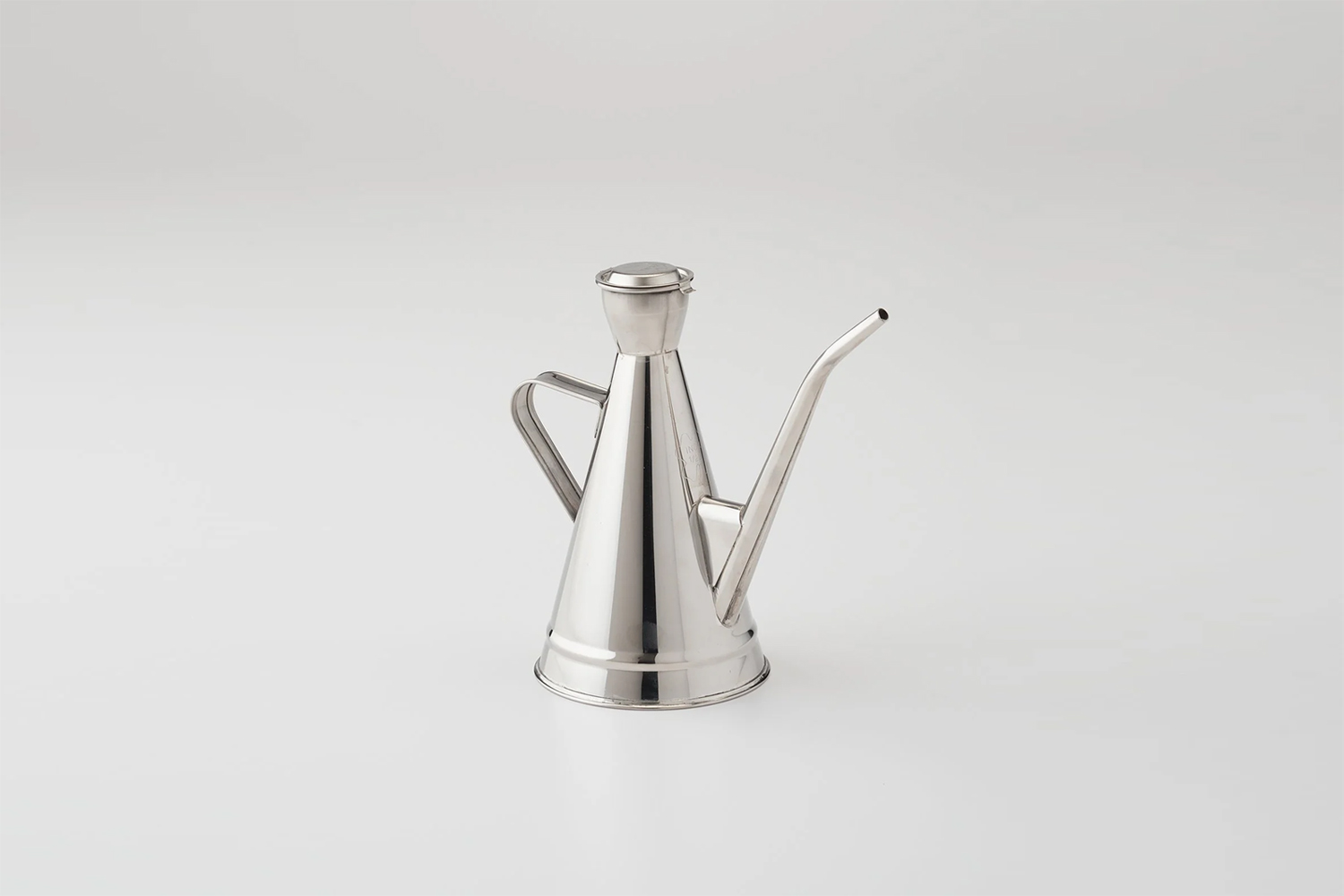 Modern minimalist kitchen accessory featuring a reflective metal olive oil cruet with a long precision spout.