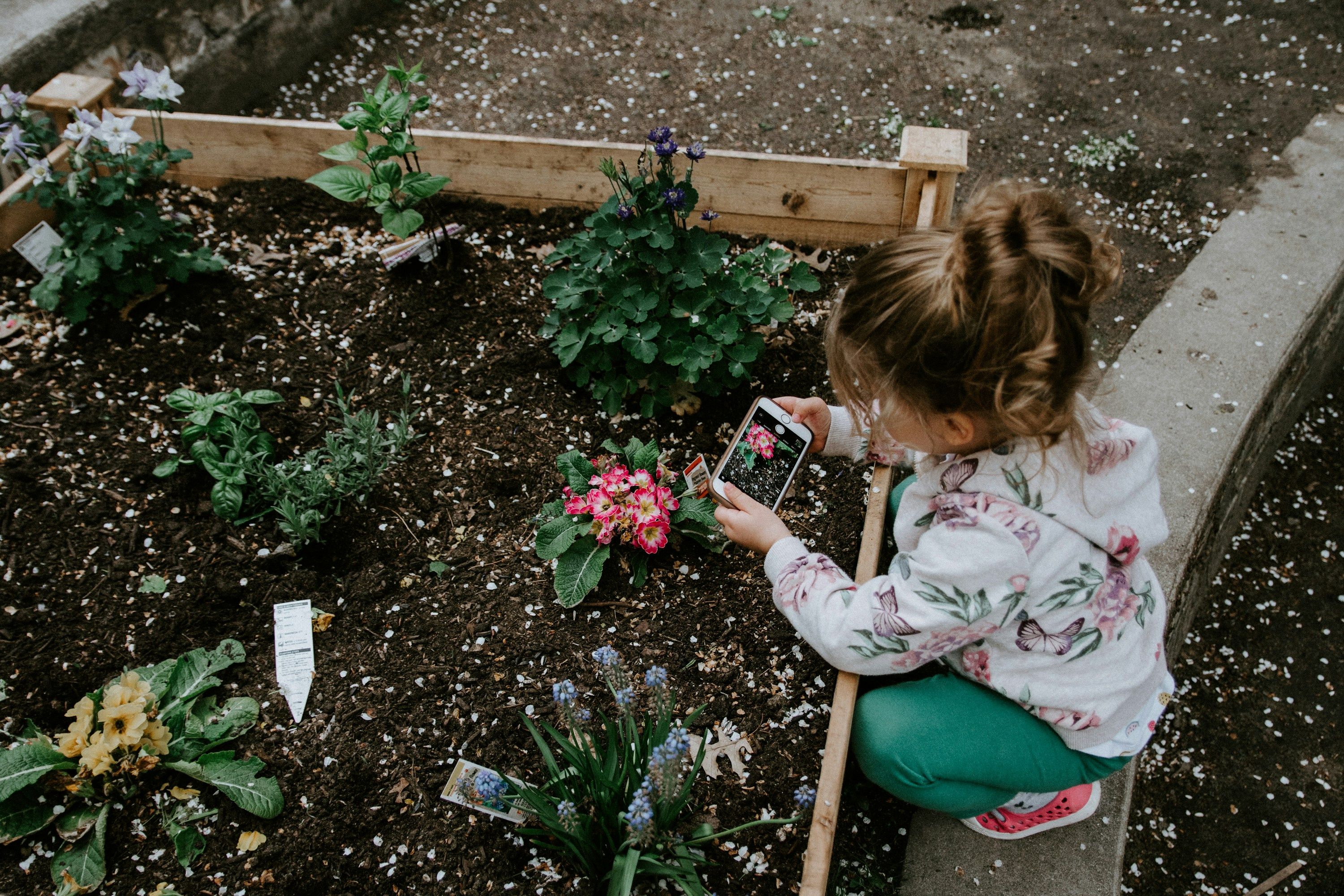 Graphic text overlay reading 'How to Garden With Your Kids (Without Losing Your Mind)' over a background of lush greenery.