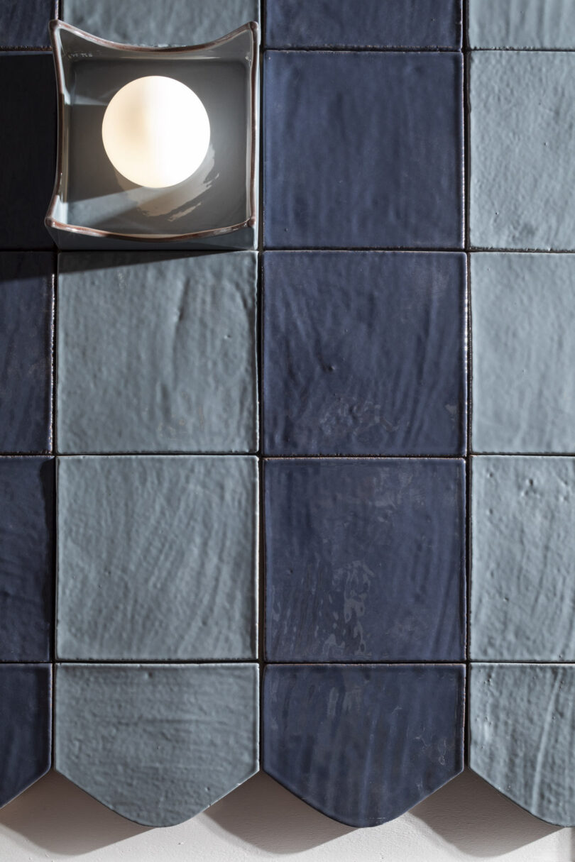 Detail of a round bulb mounted on a blue tile with scalloped textures and visible glazed finish.
