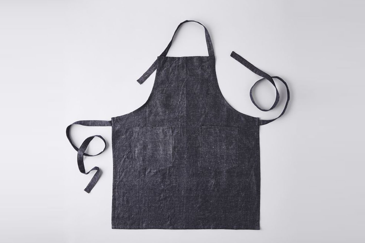 A clean, adjustable linen cotton apron in a neutral tone.