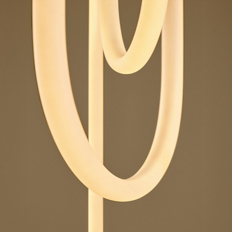 Close-up detail of two intersecting glowing curved light tubes.