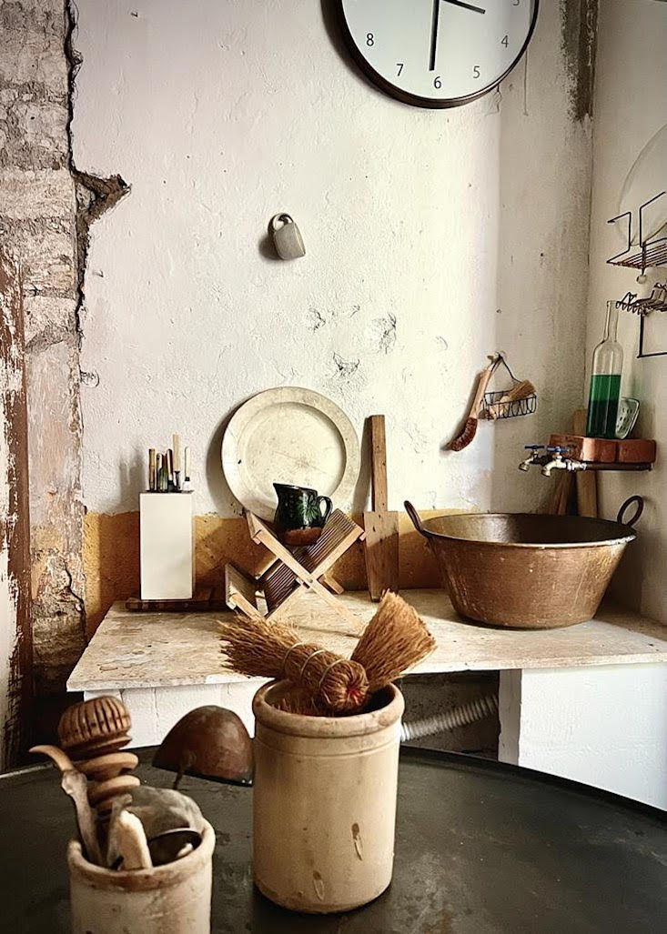 A large copper pot repurposed as a kitchen sink with brass taps.