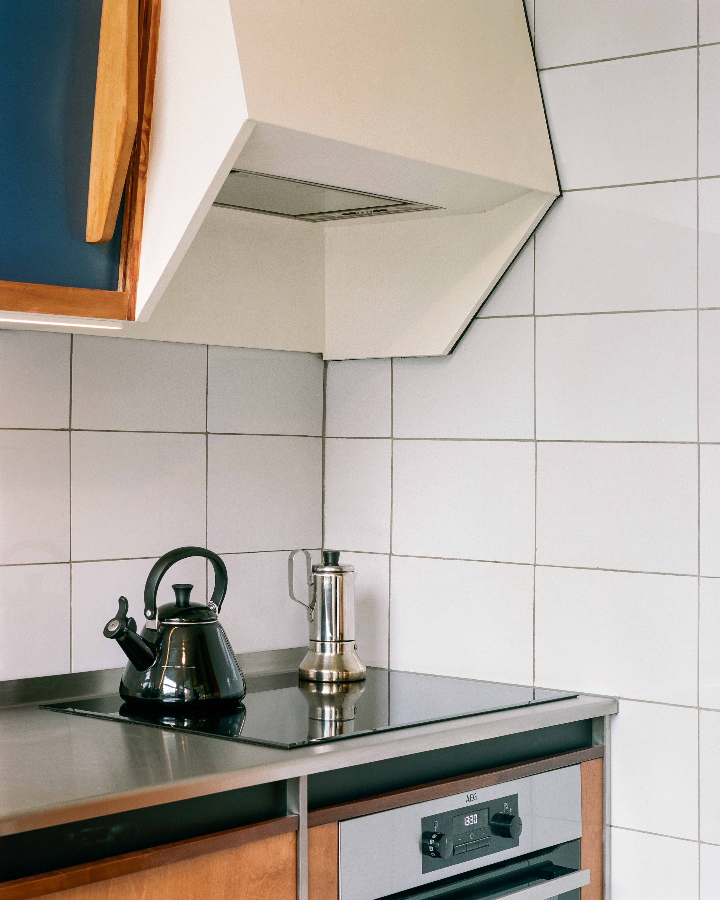 An AEG induction cooktop integrated into a stainless steel countertop within the mid-century kitchen layout.