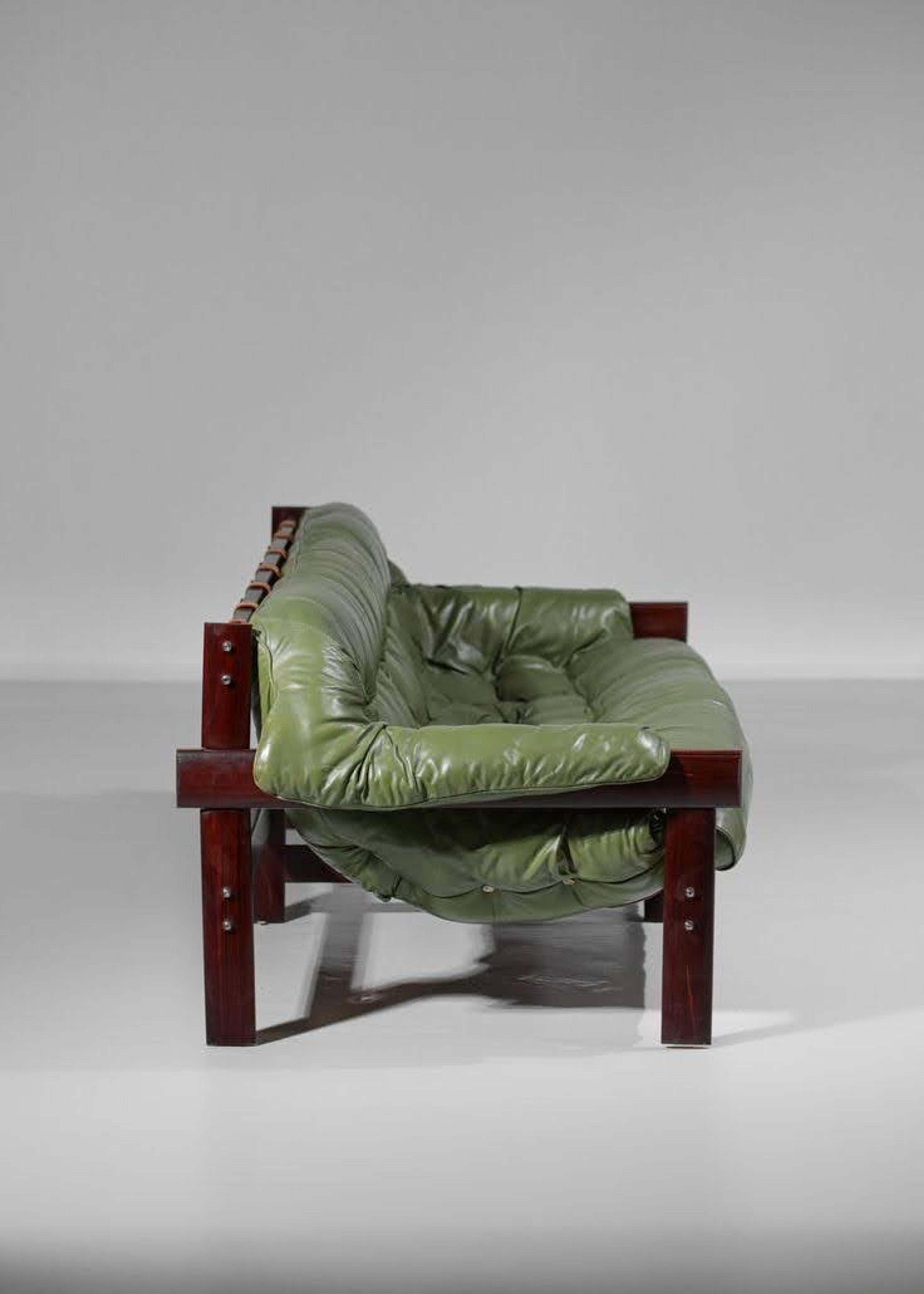 A contemporary tufted armchair in deep forest green leather