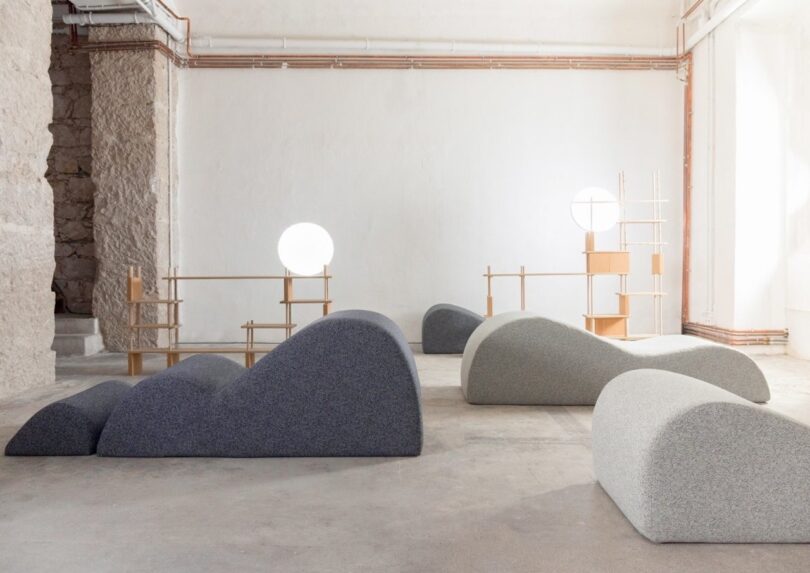 Industrial loft interior with sculptural foam seating and minimalist wooden furniture.