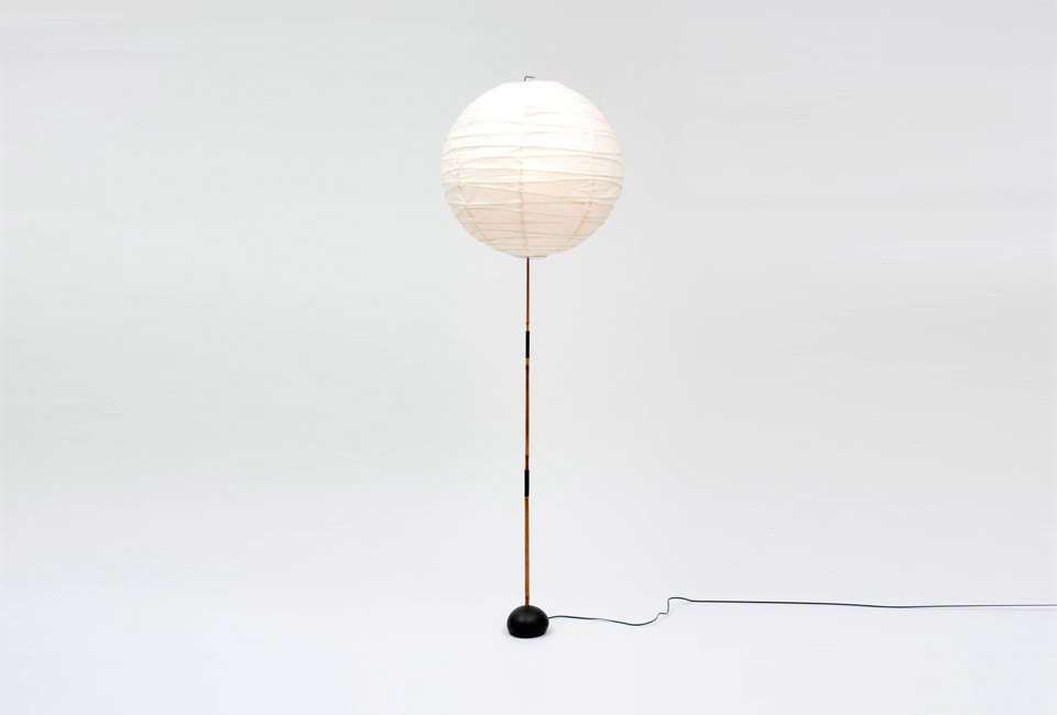 A classic Noguchi Akari paper floor lamp emitting a soft, warm glow.