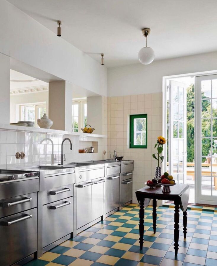Modern kitchen with blue and yellow checkerboard flooring and natural wood dining table.