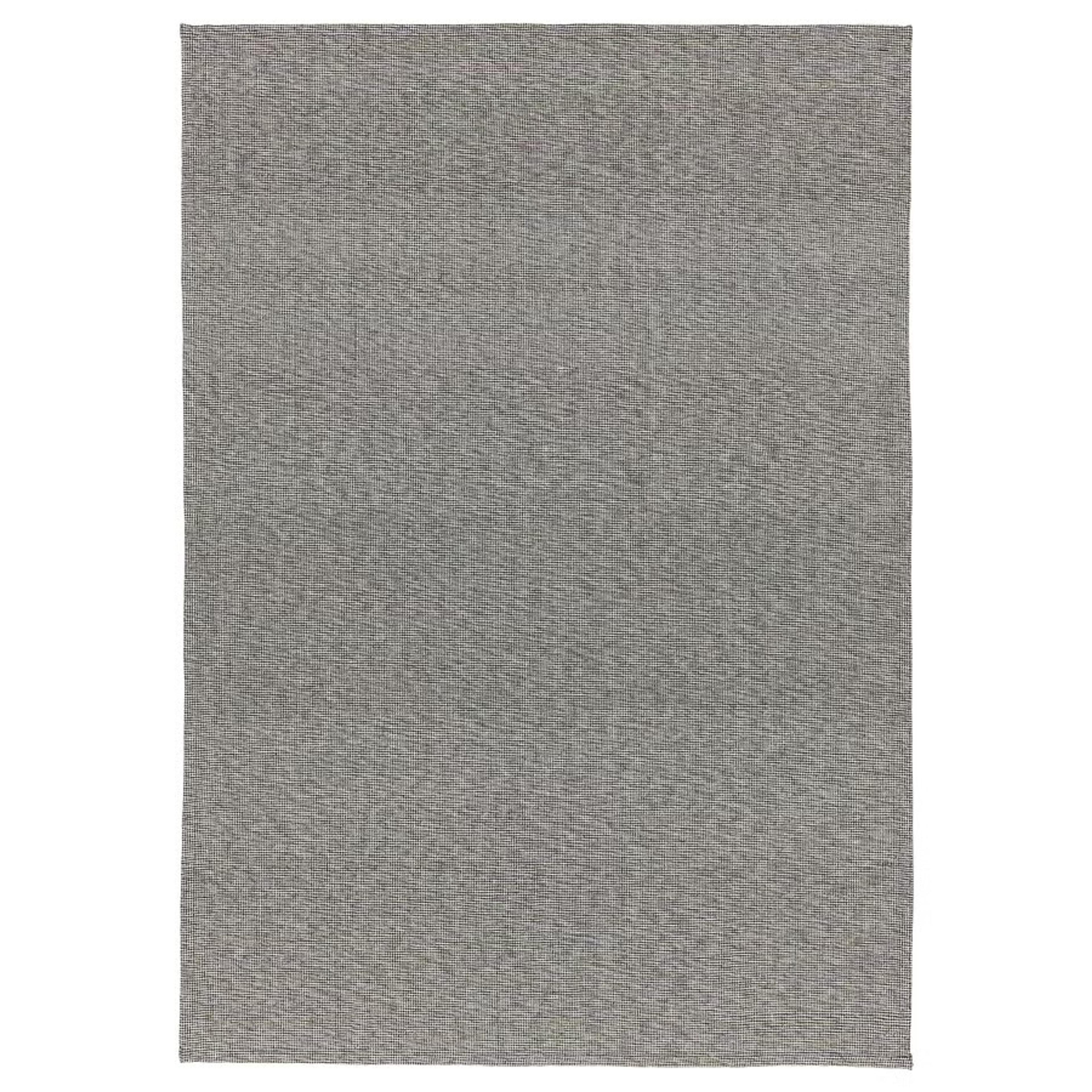 A minimalist gray IKEA Tiphede cotton rug on a wooden floor.